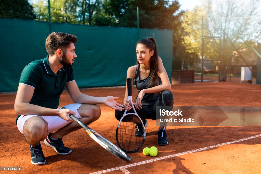Winning team Teenage girl playing tennis with her coach on clay tennis court Tennis Stock Photo
