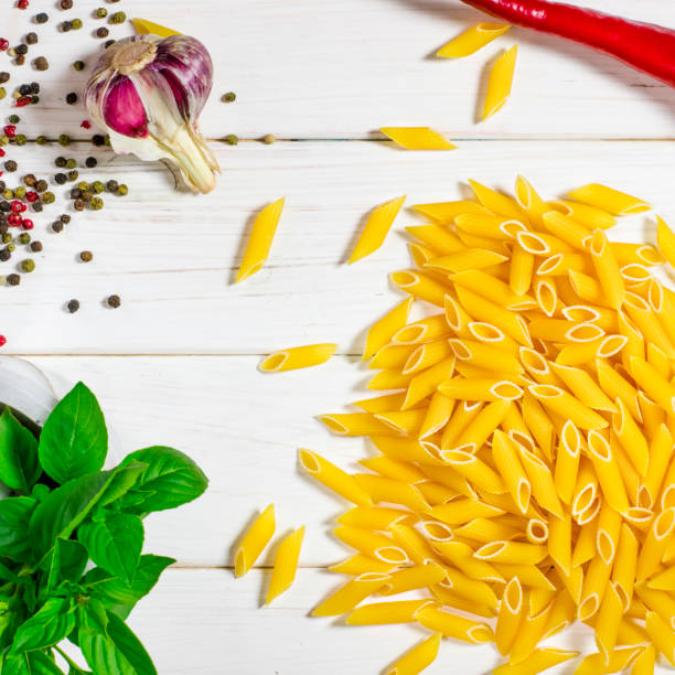 istock Penne Pasta, green basil, parmesan, sesame, garlic, chilli, eggs lie on a white tree table 1178991146