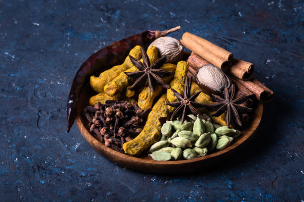 Dry warming Indian spices on plate for autumn winter meal on dark blue concrete background. Dry warming Indian spicesin on plate for autumn winter meal on dark blue concrete background. Exotic vitamin, flavor, alternative medicine, Ayurvedic. Turmeric, cinnamon, clove, cardamom, pepper, anise. ayurveda cardamom star anise spice stock pictures, royalty-free photos & images