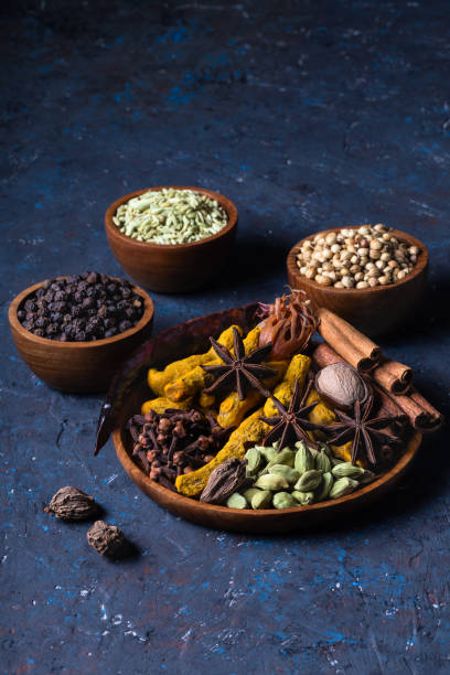 Dry warming Indian spices on plate for autumn winter meal on dark blue concrete background. Dry warming Indian spicesin on plate for autumn winter meal on dark blue concrete background. Exotic vitamin, flavor, alternative medicine, Ayurvedic. Turmeric, cinnamon, clove, cardamom, pepper, anise. ayurveda cardamom star anise spice stock pictures, royalty-free photos & images