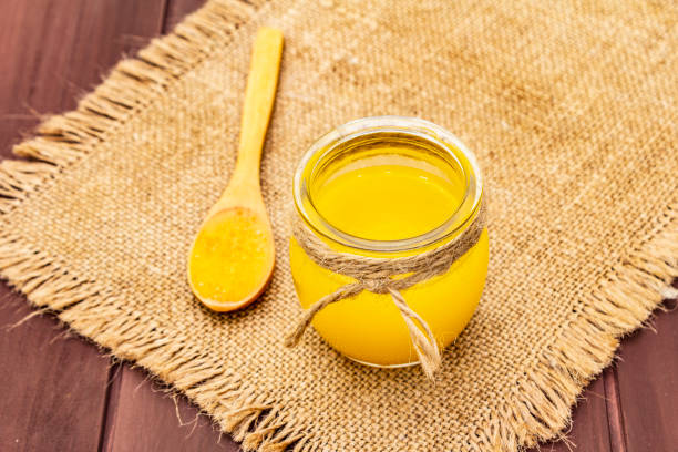 Pure or desi ghee (ghi), clarified melted butter. Healthy fats bulletproof diet concept or paleo style plan Pure or desi ghee (ghi), clarified melted butter. Healthy fats bulletproof diet concept or paleo style plan. Glass jar, wooden spoon on vintage sackcloth. Wooden boards background, copy space ghee stock pictures, royalty-free photos & images