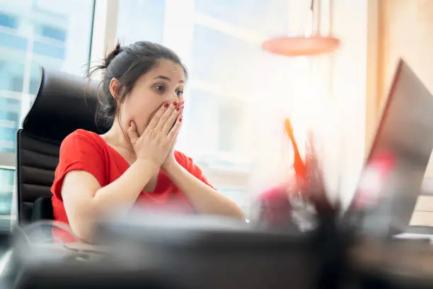 Photo of Shocked young woman looking at laptop screen