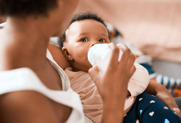 Making sure she grows into a heathy and strong princess Shot of a mother feeding her adorable infant daughter at home baby bottle stock pictures, royalty-free photos & images