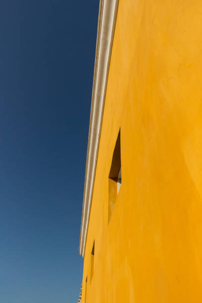 Yellow facade of a building contrasts with the blue of the sky. Cartagena de Indias, Colombia.