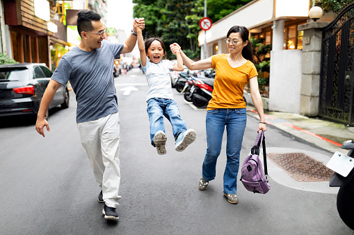 Taiwanese ethnicity parents taking their little girl to her first they at school and making the walk to school as enjoyable as possible
