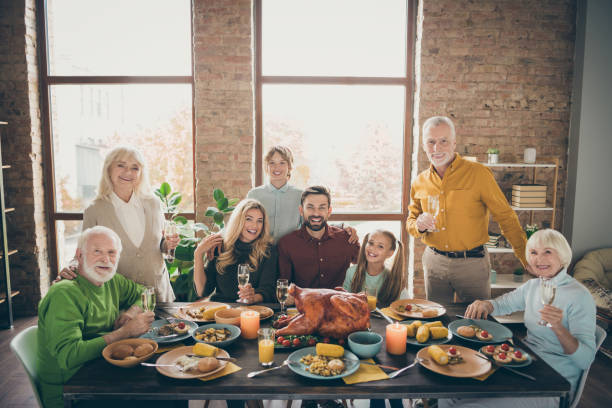 foto di grande famiglia seduta abbracciando festa tavolo vacanza tacchino arrosto facendo ritratto otto parenti moglie marito multi-generazione sollevare bicchieri di vino in soggiorno al chiuso - thanksgiving dinner party feast day turkey foto e immagini stock