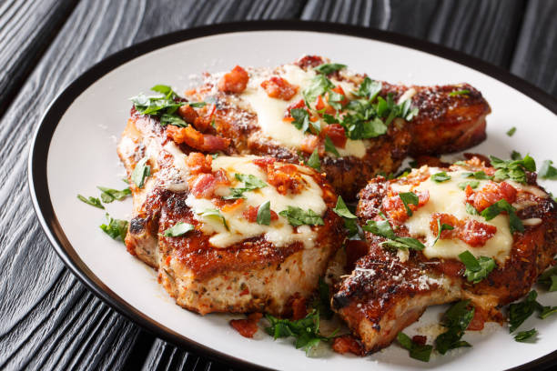 Spicy fried pork chops with melted cheese and bacon closeup on a plate. horizontal