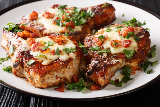 istock Cooked juicy pork chops with parmesan and bacon closeup on a plate. horizontal 1179005477