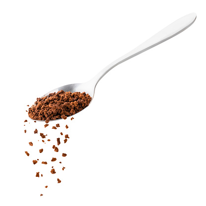 Instant coffee spills from a spoon on a white background. Isolated