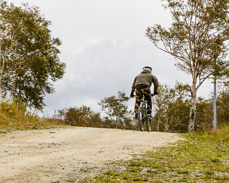 A man descends a MTB trail in the middle of nature on a sunny day.
