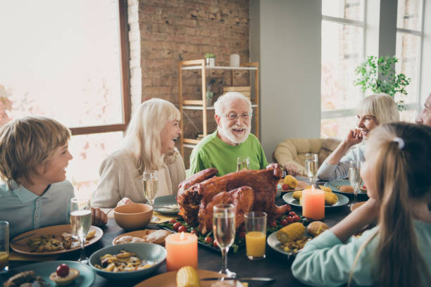 photo de réunion de réunion de réunion de réunion de famille complète s'asseyant des plats de festin table de dîner de dinde communiquant l'automne novembre vacances multi-génération tous les âges dans le salon de soirée à l'intérieur - thanksgiving dinner party feast day turkey photos et images de collection