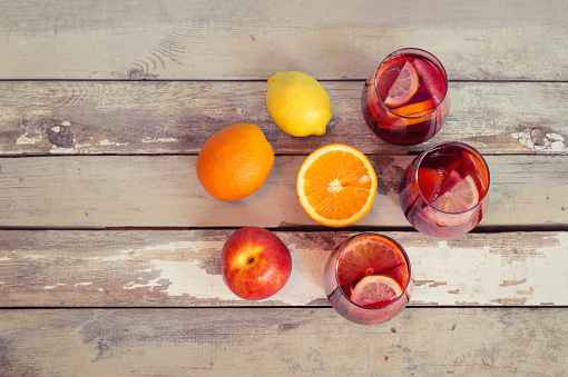 Red wine sangria with fruits in glasses and fresh fruits near on aged wooden background. Copy space, top view.