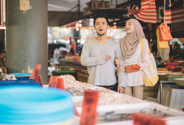 an asian malay couple buying fish from the fish stall in wet market during weekend an asian malay couple buying fish from the fish stall in wet market during weekend malay couple stock pictures, royalty-free photos & images