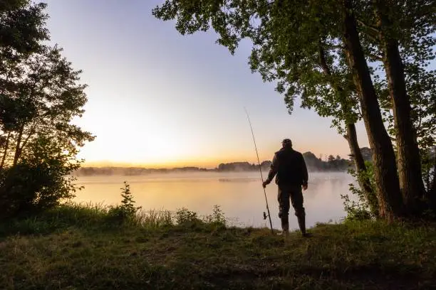 angler standing on the lake shore during sunrise