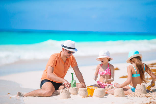 istock Father and little daughters making sand castle at tropical beach 1179009479