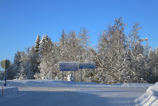 Winter wonderland called Pieksämäki, Finland, January 2019. Icy road, signs with city names & distances. snow on ground and forest. White and blue scenic landscape from Scandinavian winter.