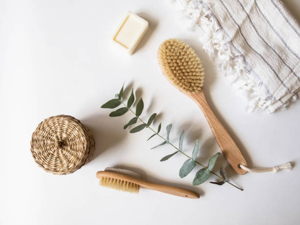 brosse de corps avec la poignée en bois, la pierre ponce, la boîte d'osier, la serviette blanche et un morceau de savon sur un fond blanc. vue du haut. - dry brush photos et images de collection