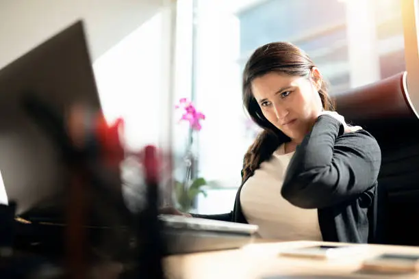 Photo of Tired businesswoman holding her nape