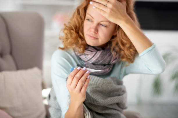 istock Curly woman suffering from flu holding thermometer 1179020761