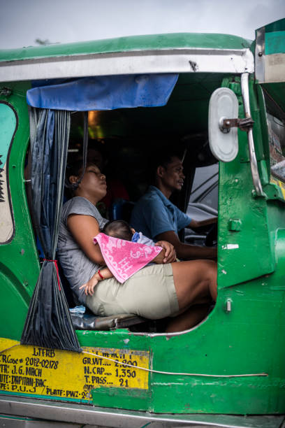 Exhaustion in Manila heat and traffic Manila, Philippines - July 24, 2019: Late on a hot July afternoon, a woman and baby sleep in the passenger seat of a jeepney moving slowly through rush hour traffic a few blocks from Rizal Park in Manila. hot filipina women stock pictures, royalty-free photos & images