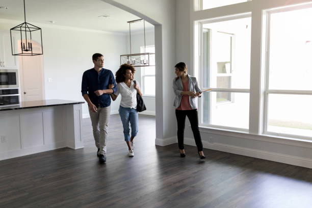 Couple meets with Real Estate Agent Real Estate Agent shows a couple a home. The Real Estate Agent shows them the home's  large living and kitchen area. The couple is expecting their first child. estate agent stock pictures, royalty-free photos & images