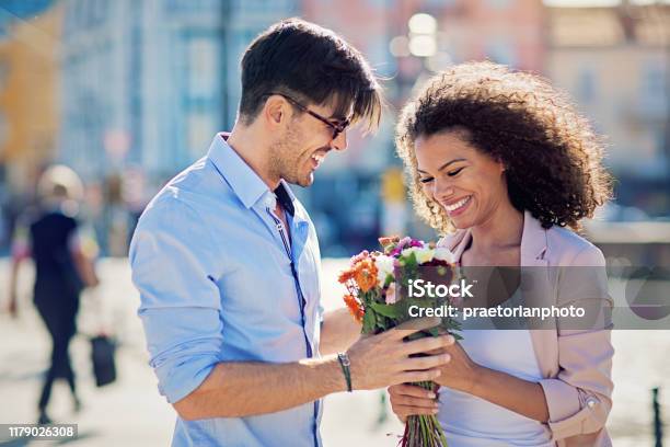Man Is Giving Flowers To His Date On The Street Stock Photo - Download Image Now - Couple - Relationship, Falling in Love, Multiracial Person