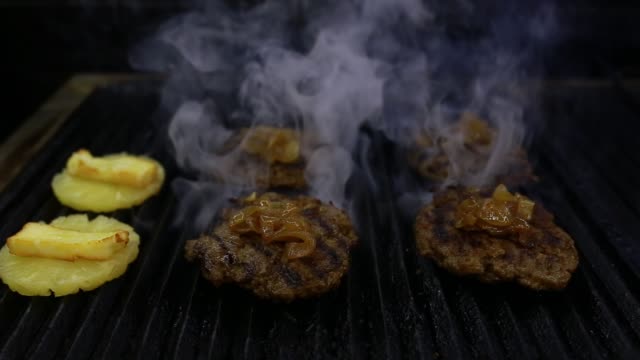 cooking pineapple and hamburger patties on the grill