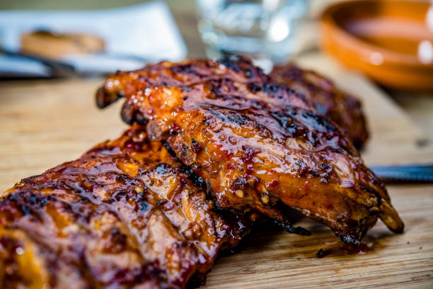 close up of golden colored juicy roasted spare ribs close up of golden colored juicy roasted spare ribs on a wooden plate carving set stock pictures, royalty-free photos & images