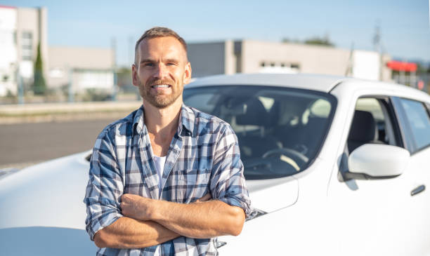 istock An attractive young man stands near a car. 1179046510
