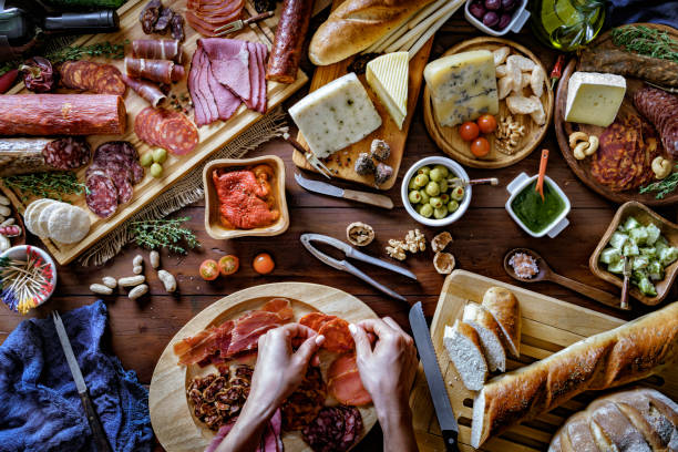 istock Female hands preparing snacks and appetizers in a set full of assorted Cured ham and cheese on rustic wood 1179047161