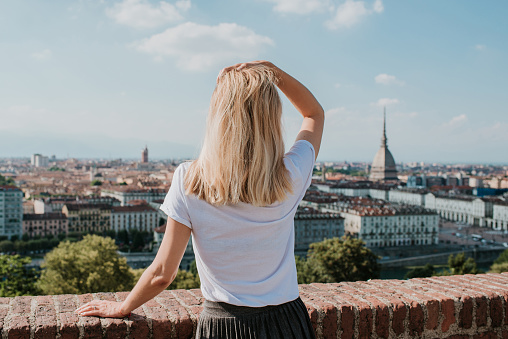 Blonde woman enjoy panorama of the Turin. Amazing scenic view on Mole Antonelliana. Girl explore Piemonte, Italy. Town and mountain. Cityscape, old historic architecture. Travel, adventure, lifestyle