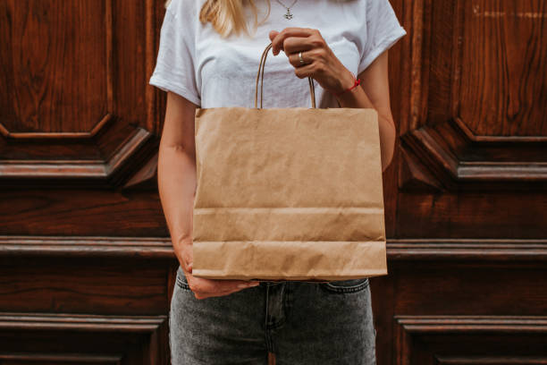 Happy blond woman with shopping package in the city. Paper bag. Sale in store. Beautiful young girl after shop. Lady buy present. Black friday sale. Holiday special offer, discount. Female love market stock photo