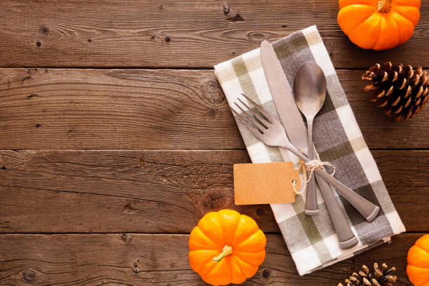 istock Blank gift tag with silverware, check print napkin, and autumn decor, top view side border against a rustic wood background 1179050237