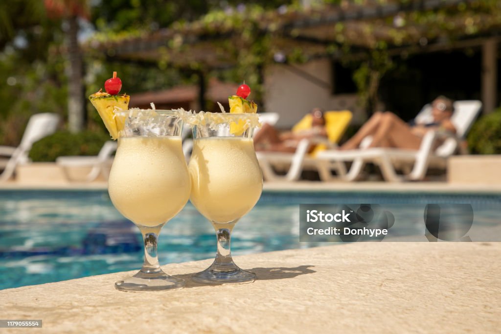 two glasses of pineapple colada at the edge of a pool Pina Colada Stock Photo