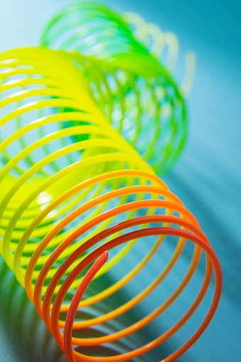 This is a plasdtic rainbow colored slinky on a turquoise blue background