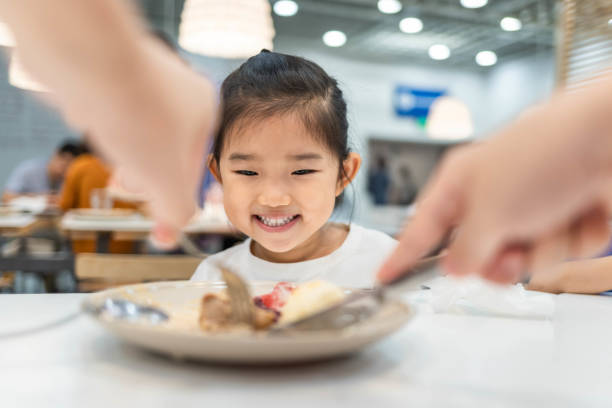 Mother helps her daughter to divide food Mother helps her daughter to divide food chinese ethnicity china restaurant eating stock pictures, royalty-free photos & images