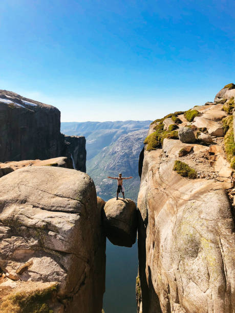 hiker standing on kjeragbolten in norway - kjeragbolten imagens e fotografias de stock