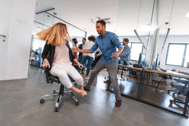 istock Playful Business Colleagues Racing Chairs Through Office 1179065030
