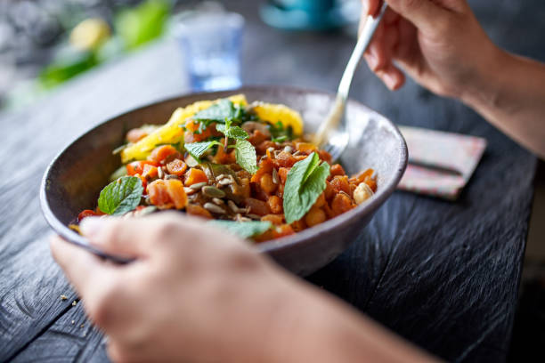 persona sana comiendo ensalada de garbanzos orgánicos de tazón con tenedor en el restaurante bohemio rústico - leguminosas fotografías e imágenes de stock