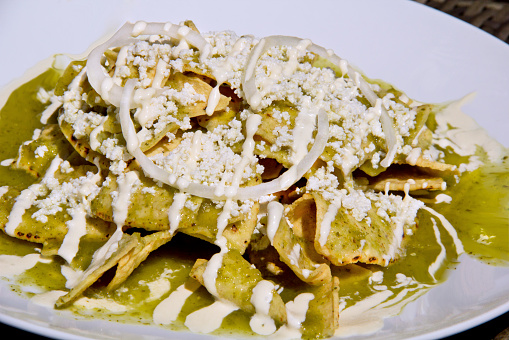 Green Chilaquiles with cheese and sour cream served in a ceramic plate