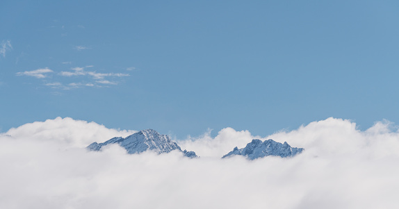 Panoramic snow mountains over white clouds and blue sky