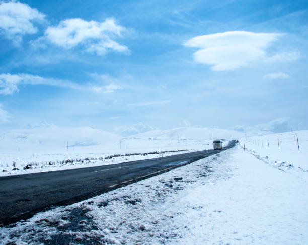 asphalt road leading towards snow mountains
