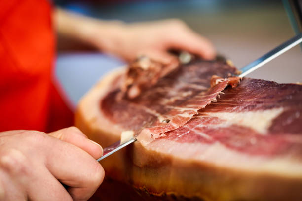 istock Professional cutter carving slices from a whole bone-in serrano ham 1179103917