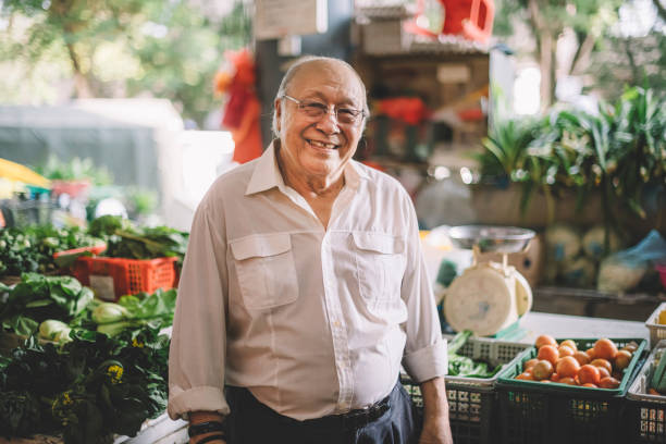 an asian senior vegetable stall owner portrait looking at camera smiling