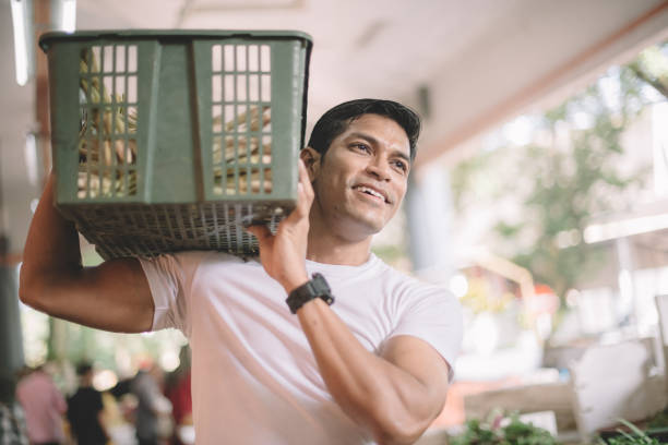an asian malay vegetable owner arranging vegetables at his stall getting ready for the day