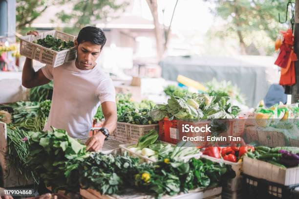 An Asian Malay Vegetable Owner Arranging Vegetables At His Stall Getting Ready For The Day Stock Photo - Download Image Now
