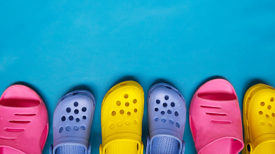 Zapatillas brillantes de colores para mujeres y niños chanclas sobre un fondo azul. Lugar para texto photo