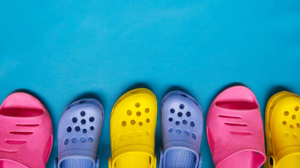 deslizadores brilhantes coloridos para mulheres e crianças flip-flops em um fundo azul. lugar para o texto - crocodilo - fotografias e filmes do acervo
