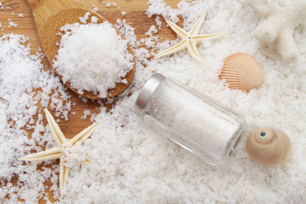 istock Salt on wooden background with salt shaker, spoon and starfish with seashells 1179115113