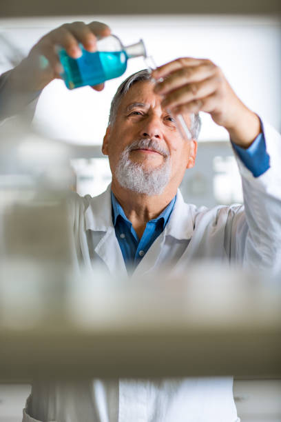 investigador masculino senior que lleva a cabo investigaciones científicas en un laboratorio - scientist lab coat doctor male fotografías e imágenes de stock